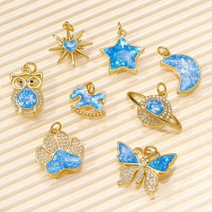 Macro detail of eight DIY gold pendants with blue opal oil drop celestial designs