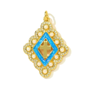 Détail d'un pendentif croix en or avec centre en résine bleue et perles synthétiques