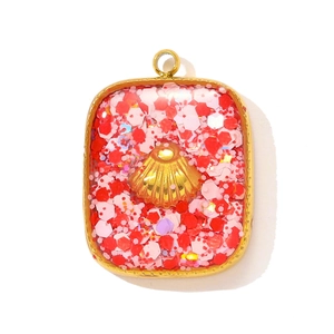 Detailed view of rectangle gold-edged shell pendant with pink and red sequins