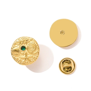 Detailed macro view of a gold marine relief brooch with seashells and a green gemstone