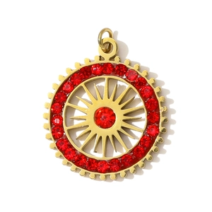 Detalle de un colgante redondo dorado con centro rojo de rayos de sol y un anillo