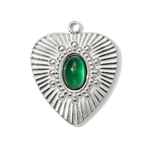 Detailed macro view of vintage heart pendant with green gemstone and sunburst texture