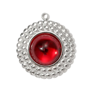 Close-up of a circular stainless steel pendant with a deep red resin stone and beaded edges