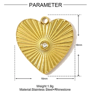 Dettaglio pendente a cuore in acciaio dorato con trama a raggiera e zircone centrale