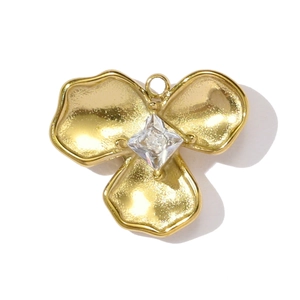 Macro shot of gold three-petal flower pendant with a sparkling square zircon center