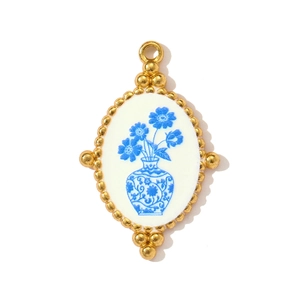 Detailed macro of oval gold pendant with blue floral porcelain pattern and beaded edge