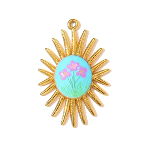 Detailed macro view of golden sunburst pendant with blue oval and pink floral pattern