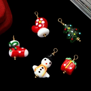 Handmade lampwork glass Christmas charms including snowman and tree on black background