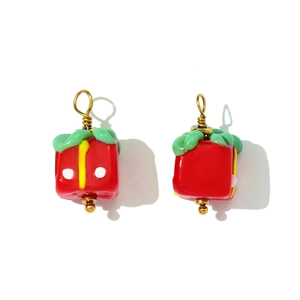 Detail of festive red gift box pendants made of glass with golden metal ring hooks