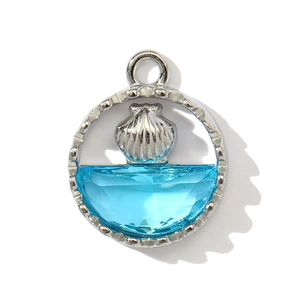Macro shot of a silver shell pendant with a blue faceted stone and nautical metal design