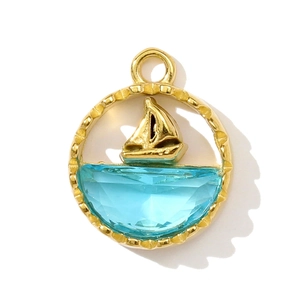Detailed macro view of a golden sailboat pendant with light blue ocean gemstone