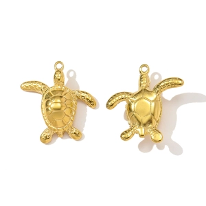 Macro view of two gold-plated turtle pendants for DIY jewelry making accessories