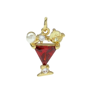 Macro shot of gold-plated cocktail glass pendant with red gemstone and white pearl