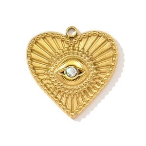 Detail of golden heart pendant featuring a central zircon and evil eye engraving design