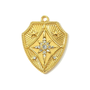 Detailed view of a gold shield pendant with a central starburst and sparkling rhinestones