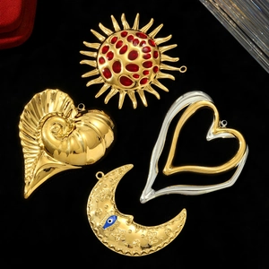 Detalle de dijes de sol, luna y corazón en acabado dorado con esmalte rojo