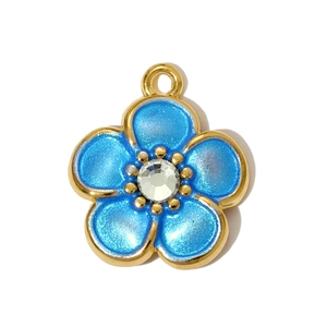 Macro shot of gold-plated flower pendant with blue enamel petals and center crystal