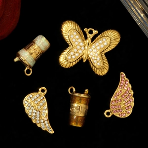 Macro view of five assorted gold-plated DIY charms featuring butterflies and coffee cups
