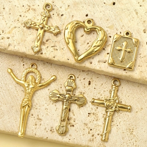 Ciondoli religiosi vintage in oro con croce e cuore su superficie in pietra