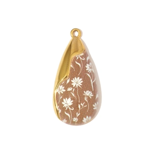 Macro detail of teardrop daisy pendant with gold metal edges and red floral pattern