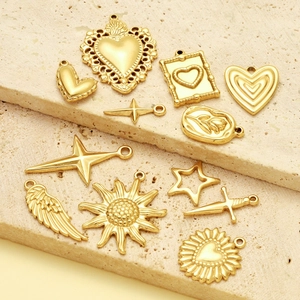 Vintage gold-plated pendants featuring heart, star, and sun motifs on stone background