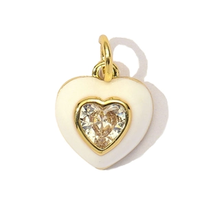Macro shot of heart-shaped gold-plated pendant with white enamel and a sparkling zircon