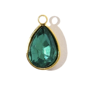 Gros plan d'un pendentif en cristal vert en forme de goutte avec monture en acier doré