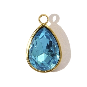 Détail d'un pendentif en cristal bleu clair taillé en goutte avec monture dorée