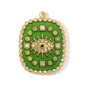 Detailed macro view of gold titanium steel pendant with green enamel and evil eye crystals