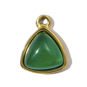 Macro shot of triangular gold stainless steel pendant with a green gemstone center