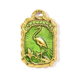 Detail of a rectangular gold-plated charm featuring a pink flamingo on a green background