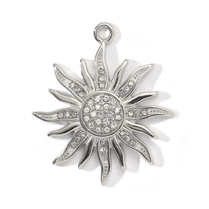 Detailed view of silver sun totem pendant with sparkling white rhinestones on white background