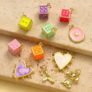Assorted enamel heart dice and gold zircon charms on a textured stone background