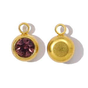 Détail d'un pendentif rond doré avec incrustation de gemme violette et dos en métal poli