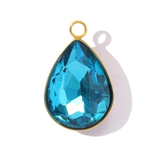 Macro shot of a faceted pear-shaped deep blue crystal pendant with gold-plated bezel