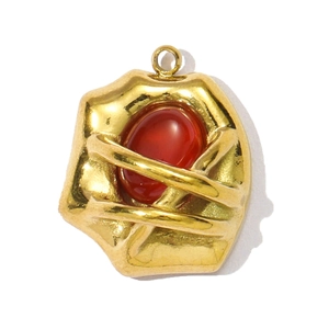 Macro shot of vintage gold stainless steel pendant with oval red stone and textured edges