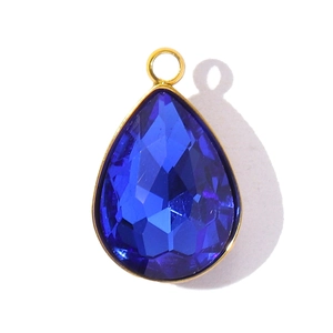 Macro shot of dark blue teardrop crystal pendant with polished gold plated metal edging