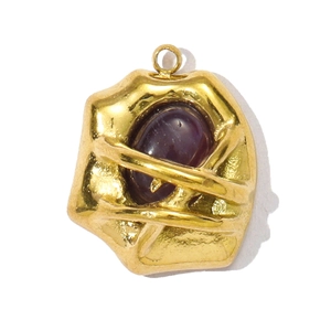 Detailed close-up of a vintage stainless steel pendant with textured gold finish and purple stone