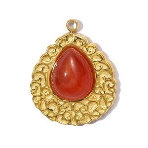 Detailed view of teardrop pendant with red agate stone and gold embossed patterns