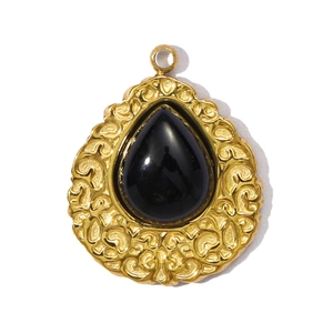 Macro detail of teardrop black stone pendant with vintage gold embossed floral texture