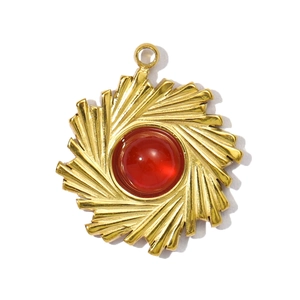 Macro shot of gold stainless steel sunburst flower pendant with red resin stone