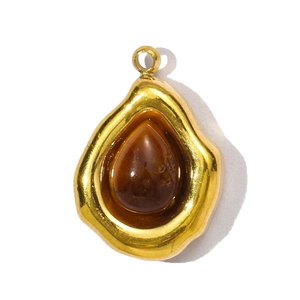 Macro detail van de gouden druppel hanger met ambersteen en lava textuur frame