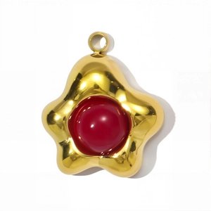 Detailopname van een vergulde sterhanger met rood emaille en een metalen ring