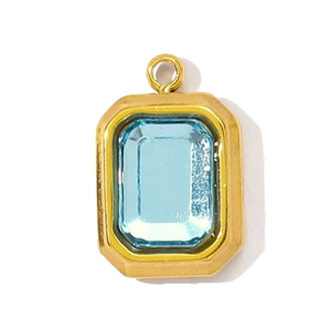 Detail of a rectangular sky blue step-cut gem pendant with a vintage gold-plated frame