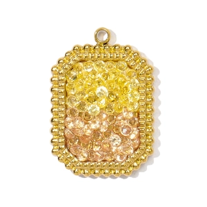 Detailed close-up of a gold-plated rectangle pendant with yellow and amber zircons