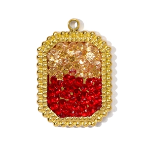 Detail of a rectangular stainless steel pendant with amber and red gemstones