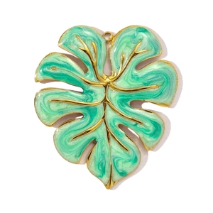 Detail of a gold monstera leaf pendant with mint green and white enamel dripping oil