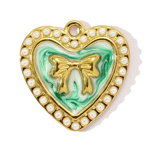 Dettaglio del ciondolo a cuore con smalto verde, fiocco dorato e perle bianche