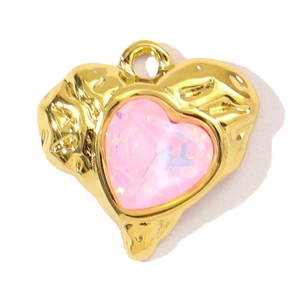 Detail of a textured golden heart pendant featuring a faceted pink crystal gemstone