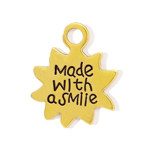 Détail d'un pendentif étoile doré avec gravure 'Made with a smile' et petit anneau